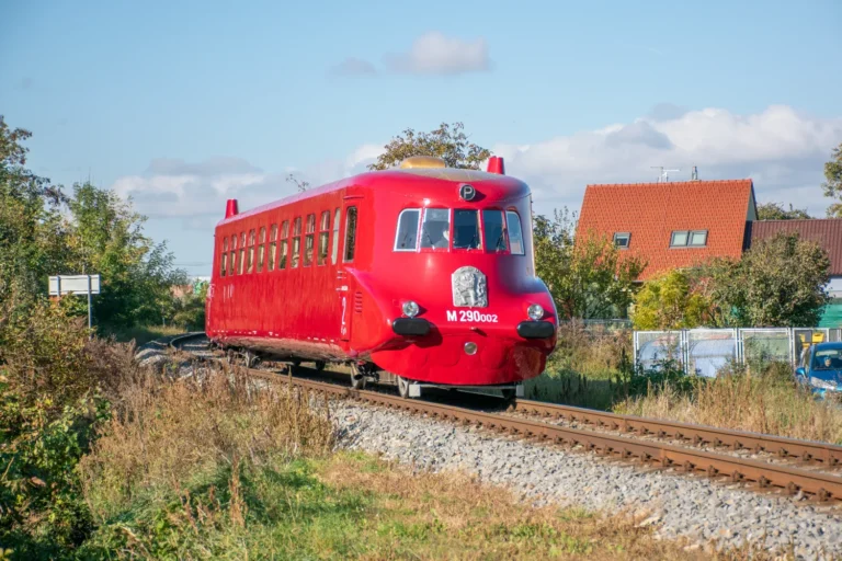 Motorový vůz Slovenská Strela (M290.002) projíždí obec Vésky za ranního slunce.